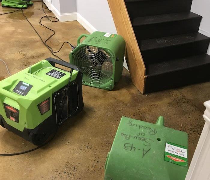 SERVPRO drying equipment set-up on basement floor by a stairwell